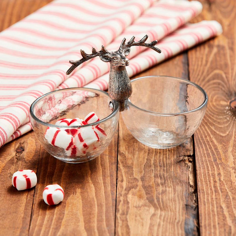 Decorative reindeer figure with a glass bowl of peppermints on a wooden table.