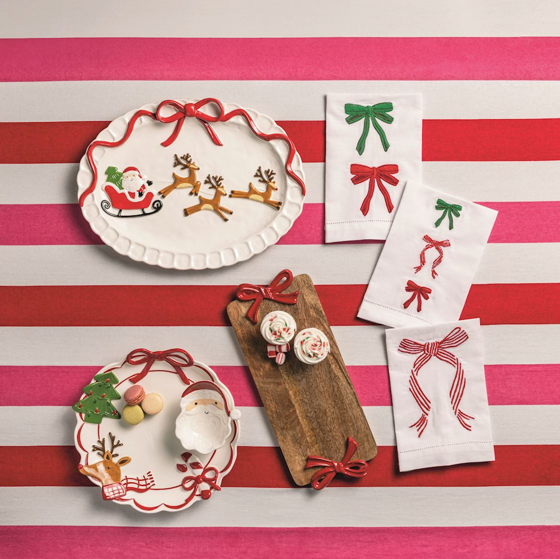 Decorative plates and towels with festive designs on a striped red and white tablecloth.
