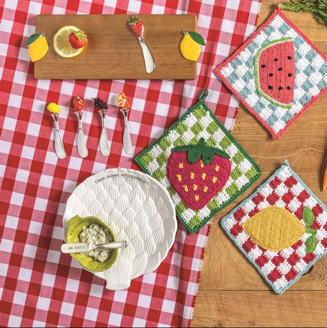 Set of decorative kitchen towels with food-themed designs on a wooden table.