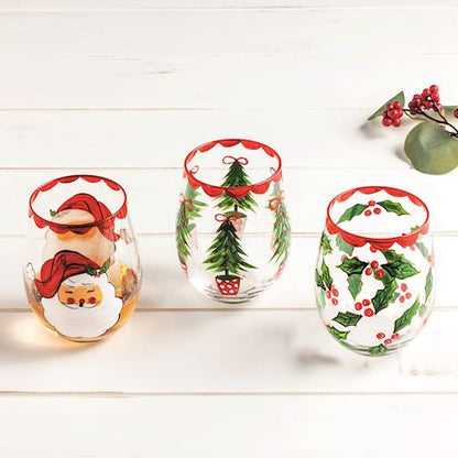 Set of three Christmas-themed stemless wine glasses on a white wooden surface.