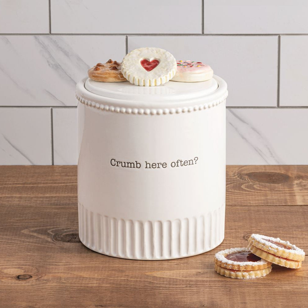 White cookie jar with cookies on a wooden surface and tiled wall background