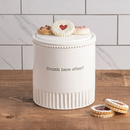 White cookie jar with cookies on a wooden surface and tiled wall background