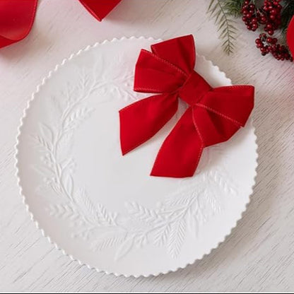 White decorative plate with a red bow on a light wooden surface.