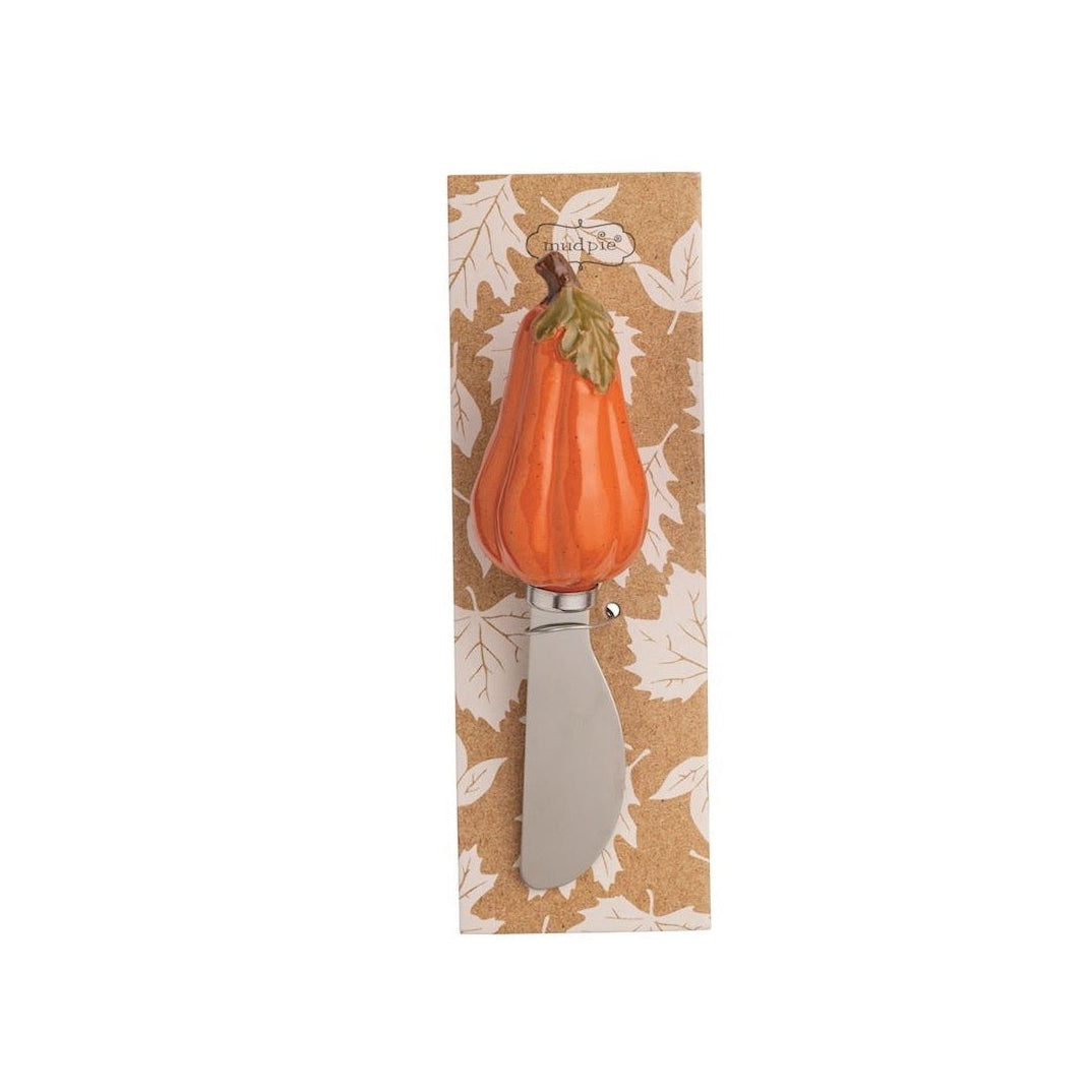A decorative kitchen knife with a sculpted orange pumpkin handle and green stem, mounted on a vertical kraft paper backing card with a white leaf pattern.
