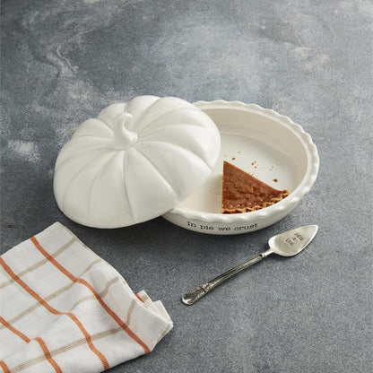 White ceramic container with a lid on a gray surface, next to a striped cloth and a spoon.